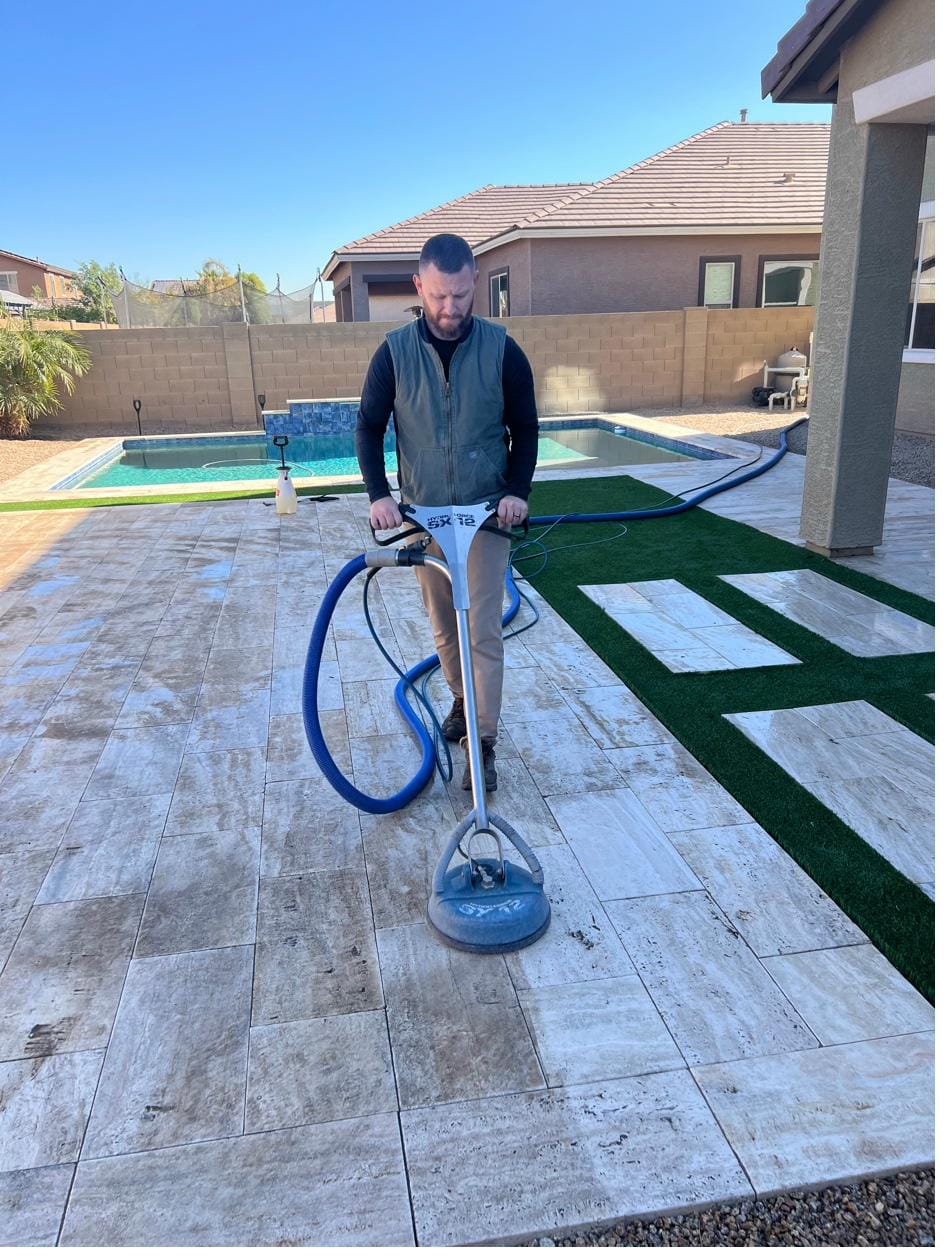 Stephan Robinson, owner of Robinson Renew, on an outdoor travertine patio with the spinner tool